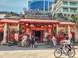 Cyclists passing a red-roofed traditional building