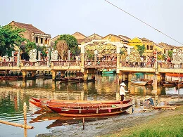 Wooden boat on a river beside waterfront buildings
