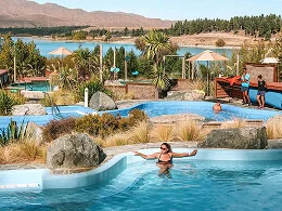 Guest swimming in a resort pool surrounded by gardens