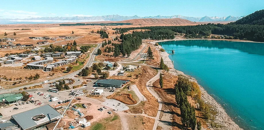 Aerial view of a turquoise lake beside roads and dry hills