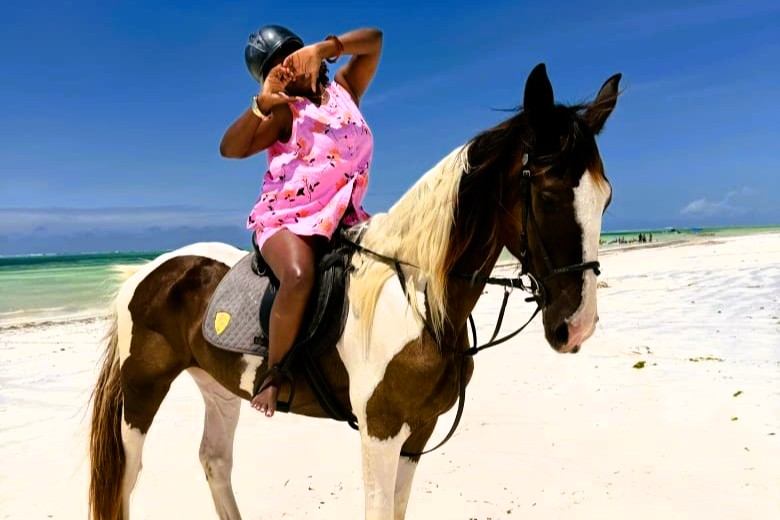 Rider on a brown and white horse beside a beach