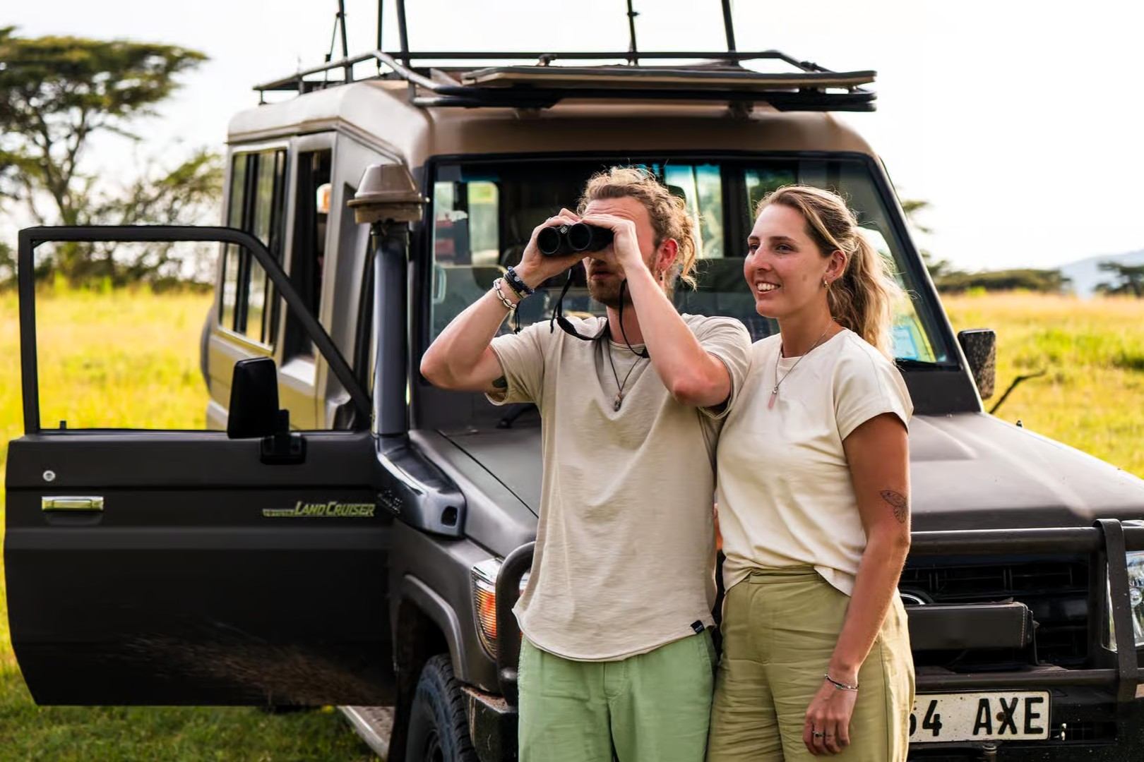 Travellers using binoculars beside a safari vehicle