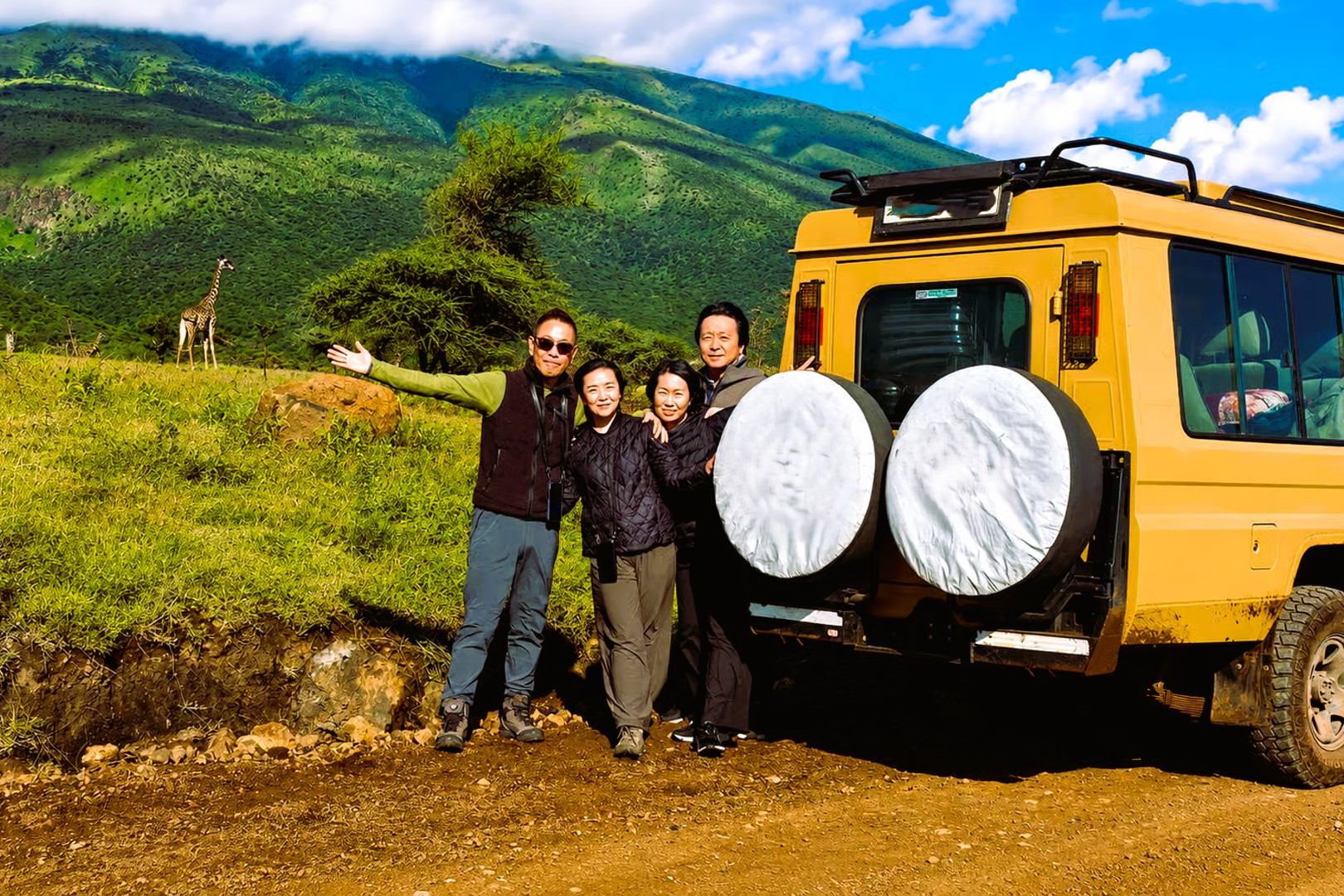 Travellers beside a safari vehicle in a green landscape