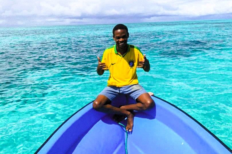Man sitting on the bow of a boat over turquoise water
