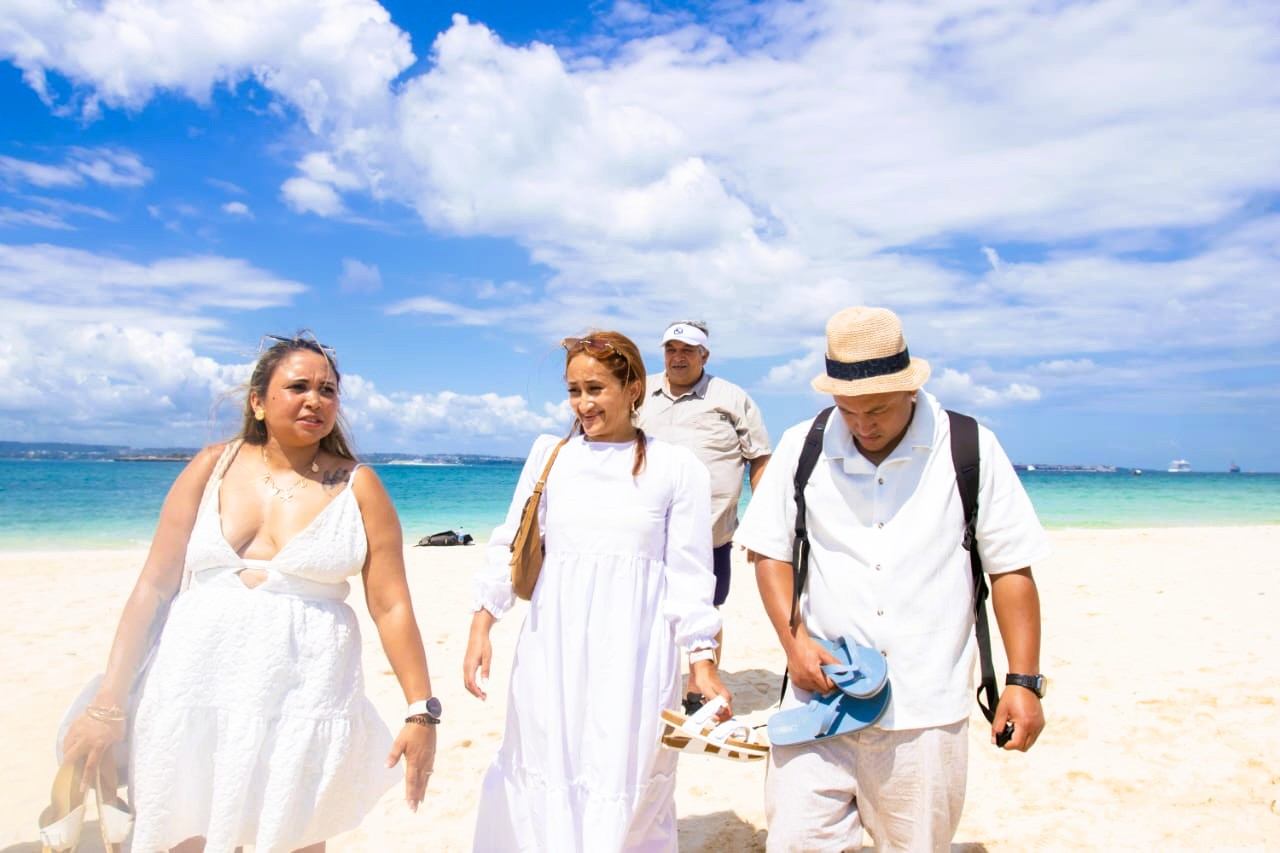 Travellers walking together across white sand beside the sea