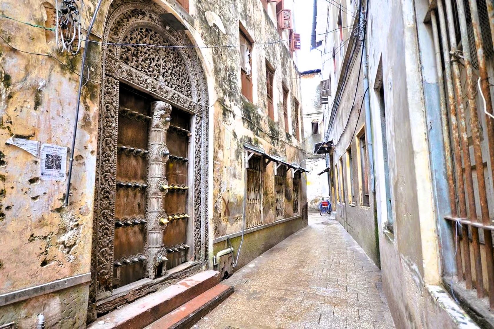 Carved wooden door beside a narrow Stone Town lane